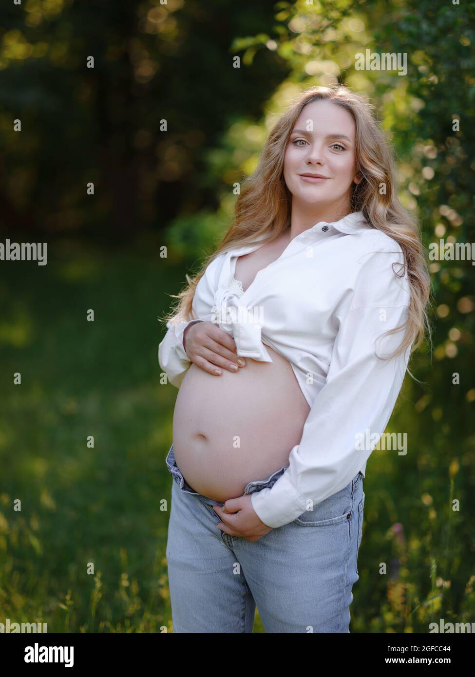 Blonde Schwangere in weißem Hemd und Jeans genießt die Stille und Schönheit  der Natur. Idee von Gesundheit und Schönheit der Schwangerschaft  Stockfotografie - Alamy