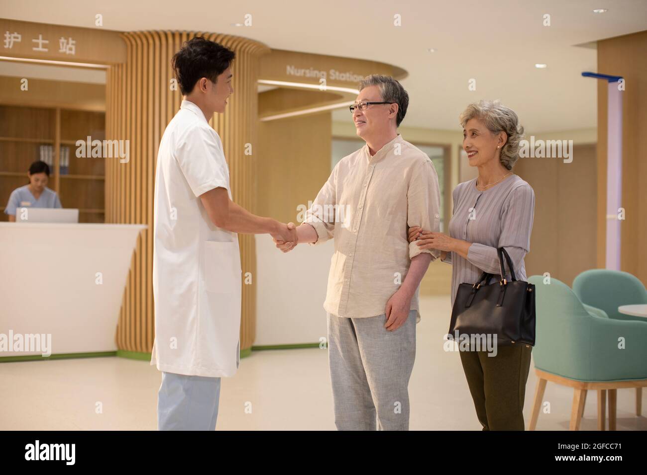 Arzt schüttelt sich die Hände mit einem älteren Paar im Krankenhausflur Stockfoto