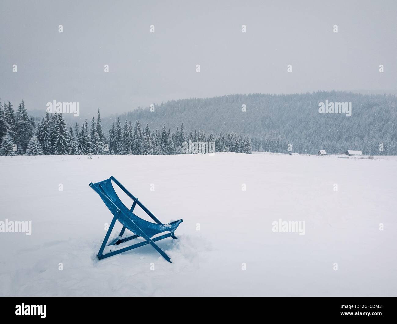 Liegestuhl auf der Spitze eines Berges an einem verschneiten Wintertag. Tannenwald bedeckt mit Schnee am Horizont. Skigebiet Bukovel, Ukrainische Karpaten Stockfoto