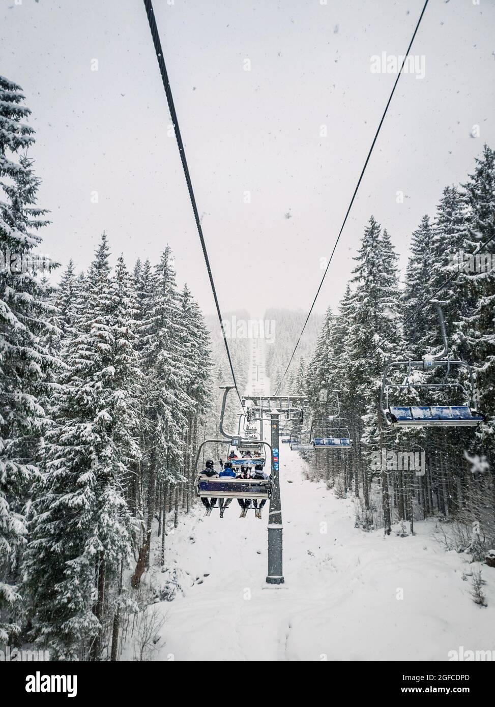 Wunderbare Winterszene mit Schneefall, während man mit der Seilbahn auf den Gipfel des Berges klettert. Skigebiet Bukovel in den ukrainischen Karpaten Stockfoto