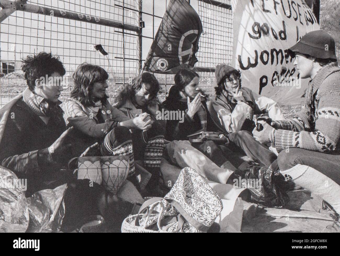 Frauen versammeln sich um den Umzäunungszaun im Greenham Common Womens Peace Camp während des Aktionstages „Embrace the Base“ vom 12. Bis 13. Dezember 1982. Stockfoto