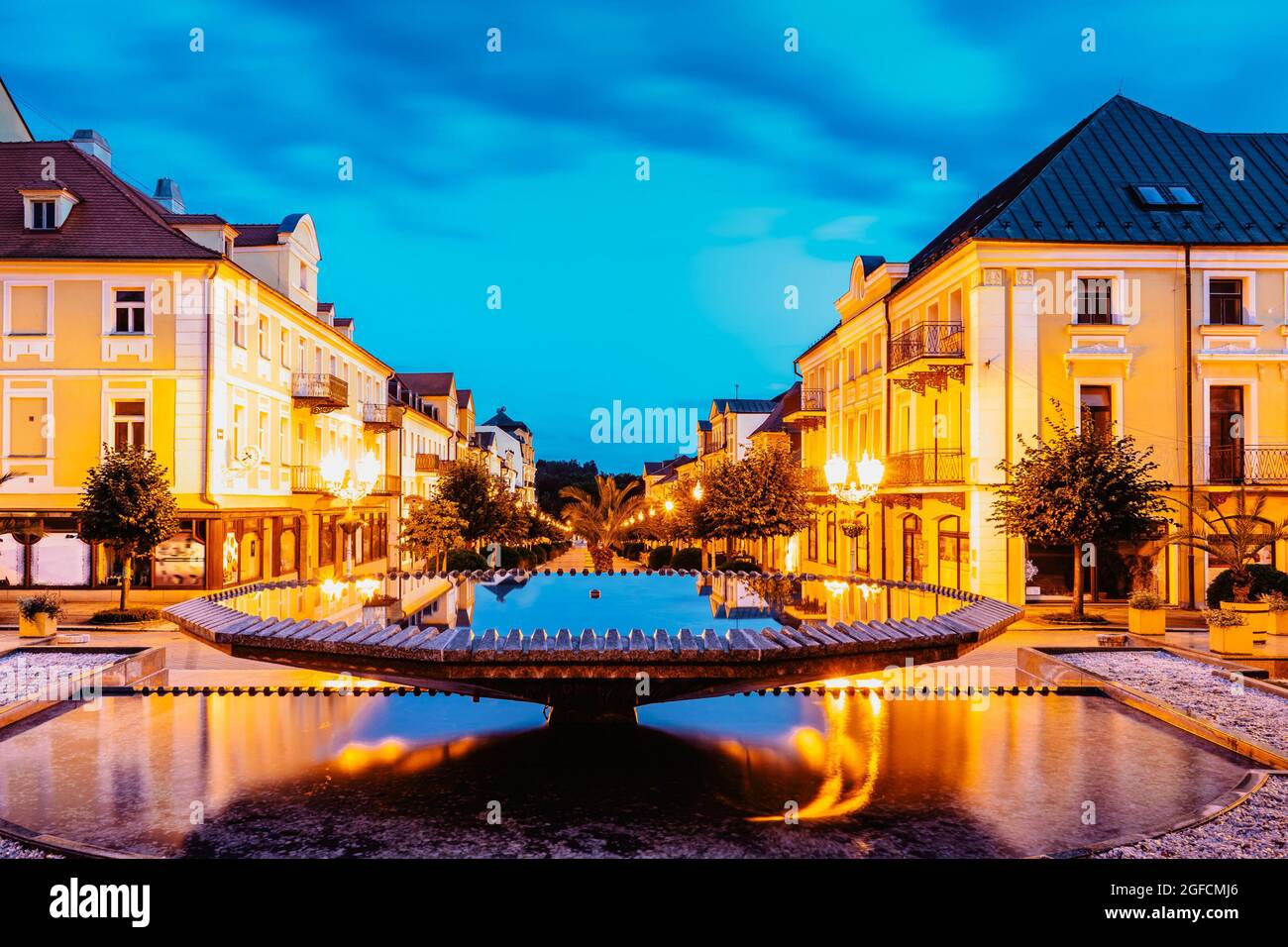 Brunnen in Frantiskovy Lazne bei Sonnenuntergang, Tschechische Republik.schöne Kurstadt in Westböhmen, Thermalgebäude mit typischer gelber Fassade, neoklassizistisch Stockfoto