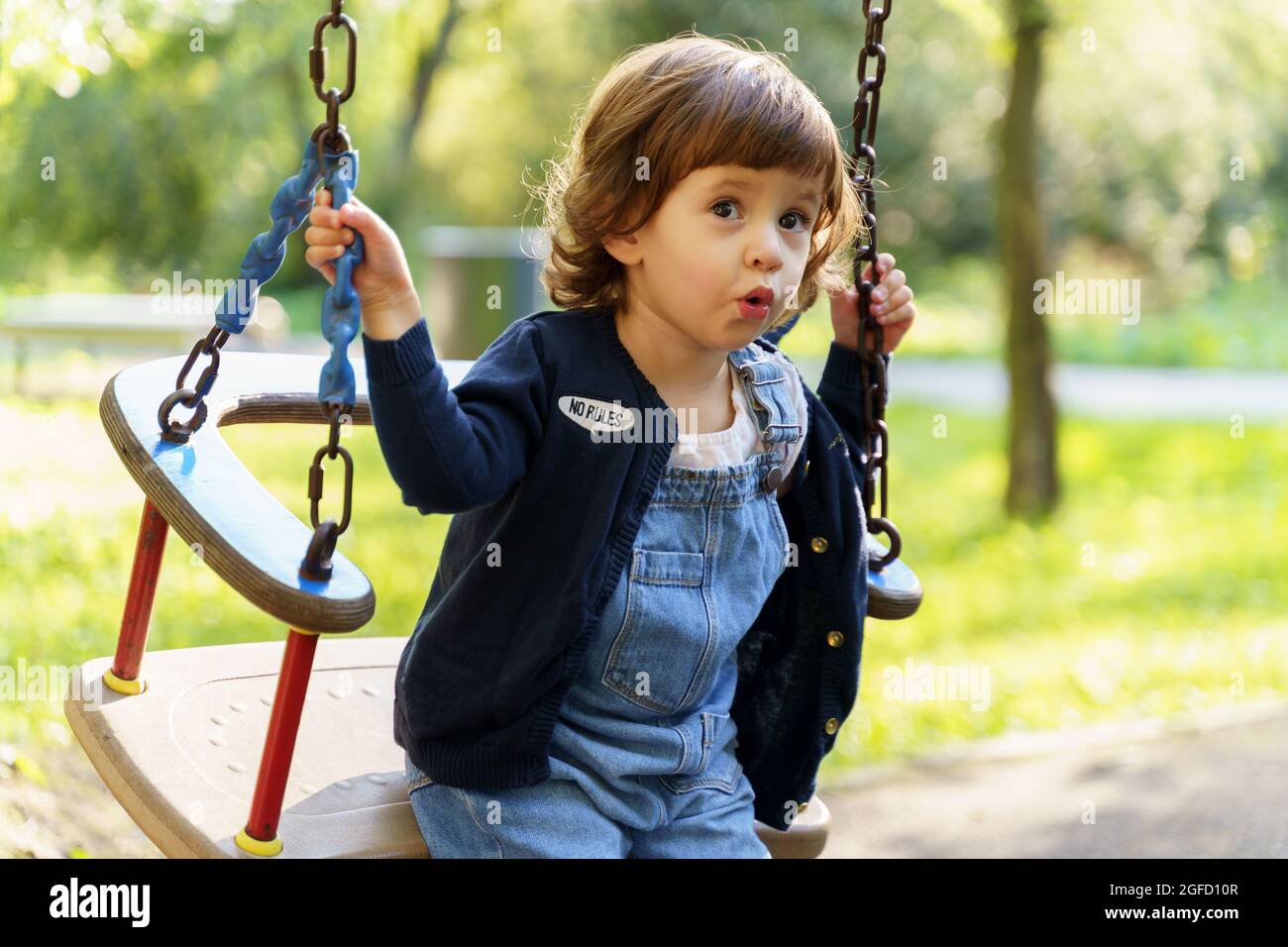 Süße kleine Kleinkind Mädchen in blauen Jeans spielen auf Schaukel im Park  im Freien Stockfotografie - Alamy