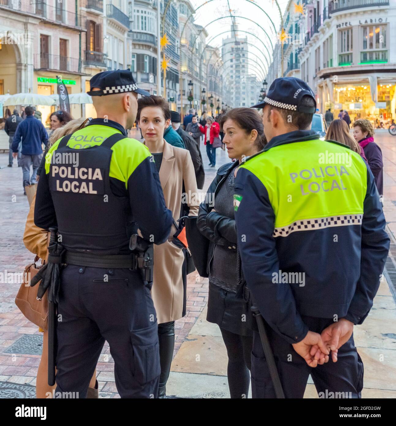 Zwei Polizisten sprechen mit Besuchern auf der Plaza de la Constitucion, Malaga, Costa del Sol, der Provinz Málaga, Andalusien, Südspanien. Stockfoto