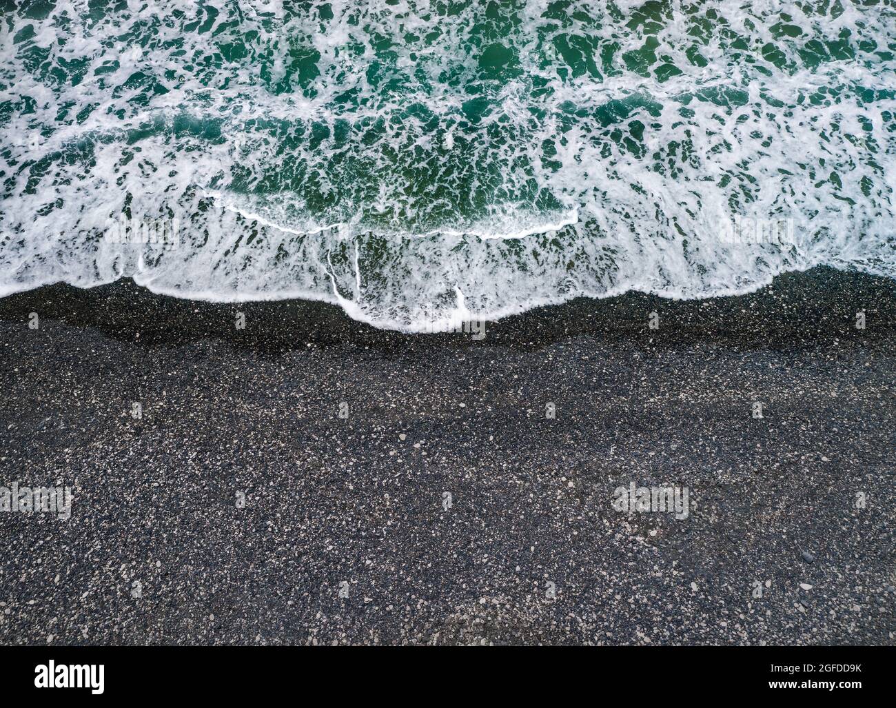 Stürmisches Wetter, Meereswellen brechen an einem Ufer mit schwarzem vulkanischem Sand, Hintergrund mit Kopierraum Stockfoto