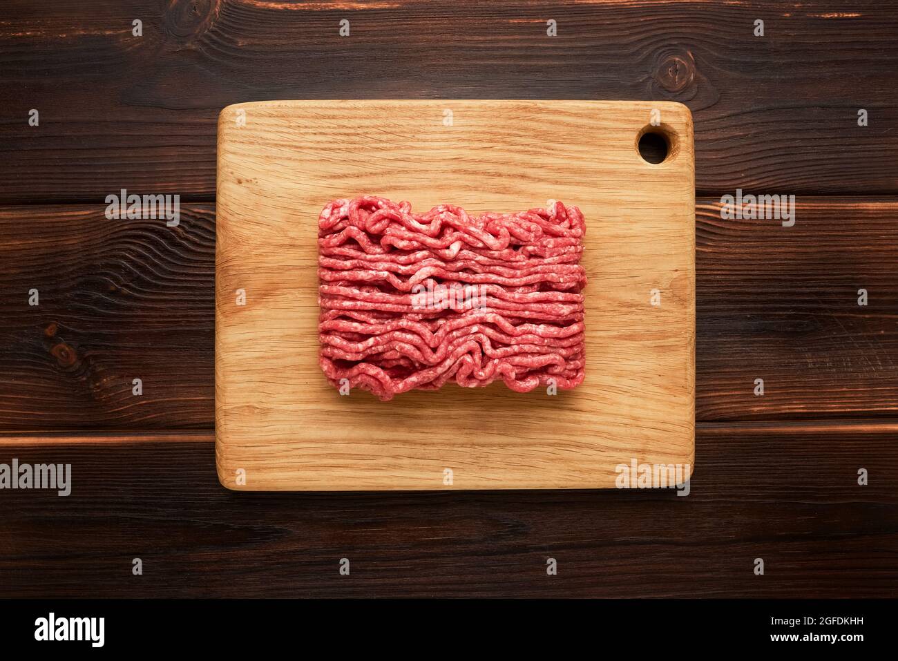 Rohes Hackfleisch, Hackfleisch oder Hackfleisch auf Schneidebrett auf Holzhintergrund. Draufsicht, Kopierbereich Stockfoto