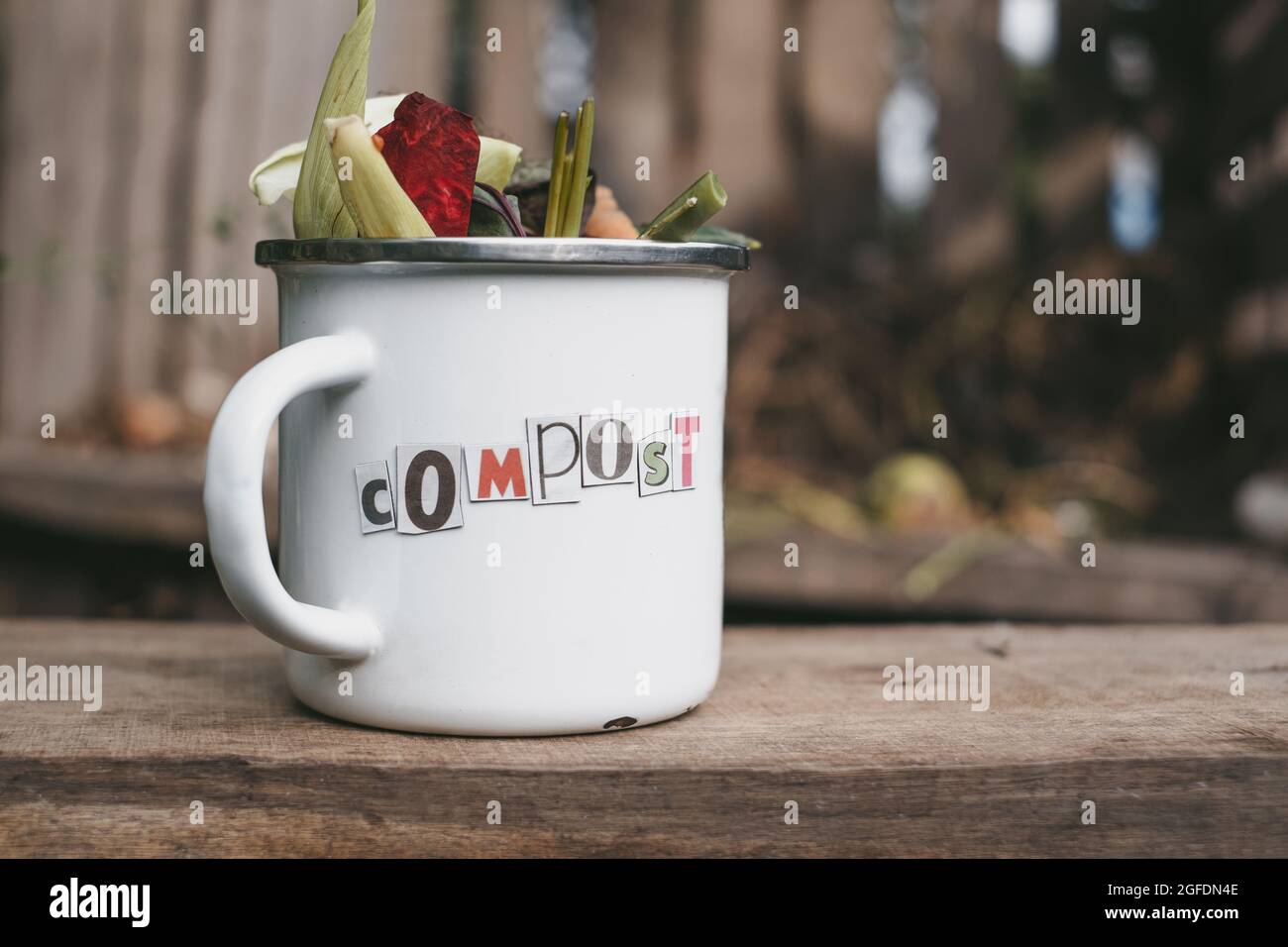 Gemüseabfall in einer Metallschüssel auf einem Holztisch. Zero Waste Worte schneiden die Zeitung aus. Hochwertige Fotos Stockfoto