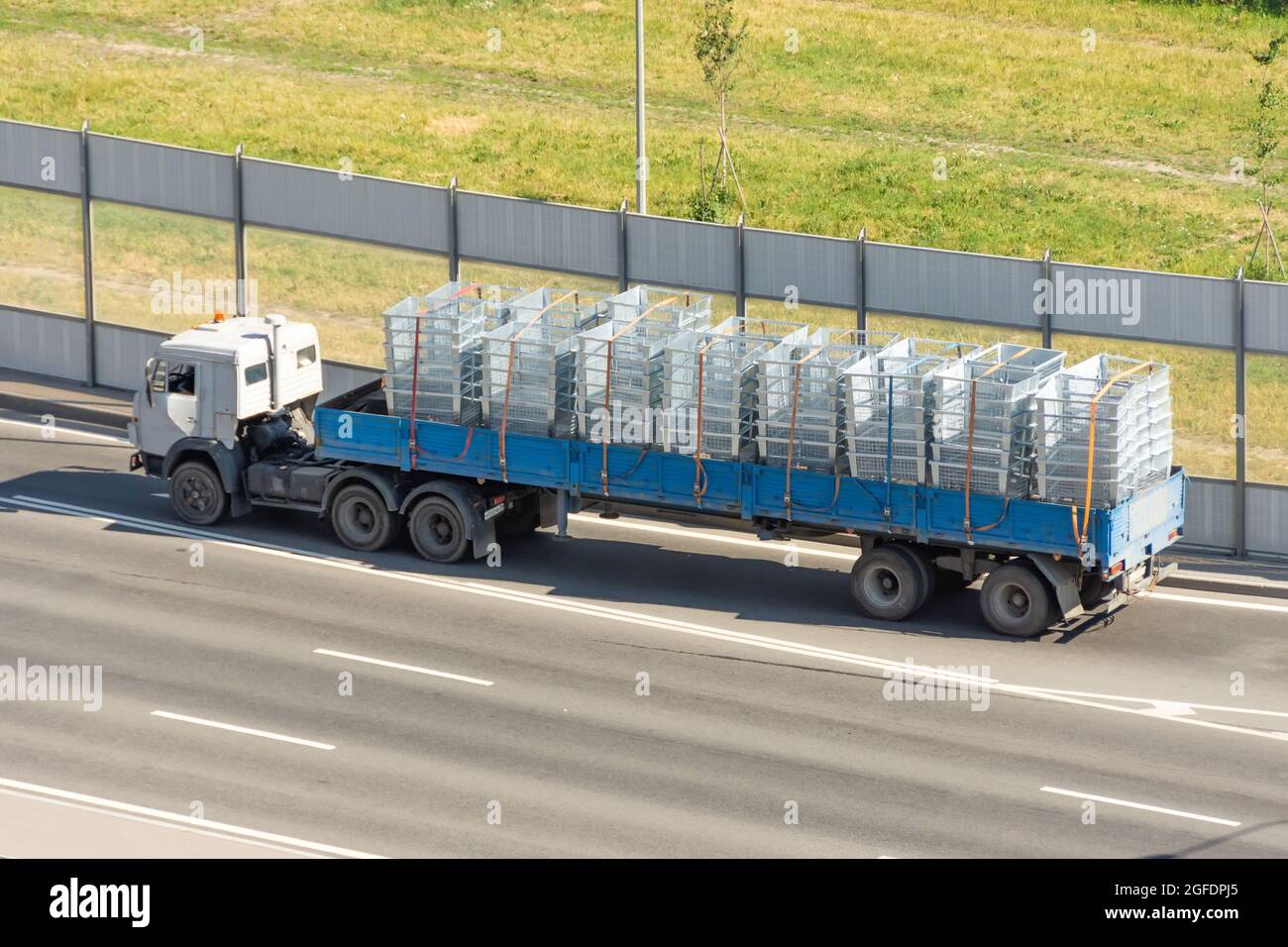 Transport und Lieferung von Fracht in einem offenen Anhänger LKW auf der Autobahn, Versandkisten, Metall Kühlergrill Ladung Stockfoto