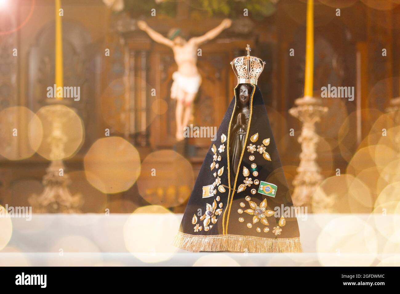 Altar mit Skulptur von Nossa Senhora Aparecida, schutzpatron Brasiliens in selektiver Ausrichtung und Kreuz Jesu Christi im Hintergrund Stockfoto