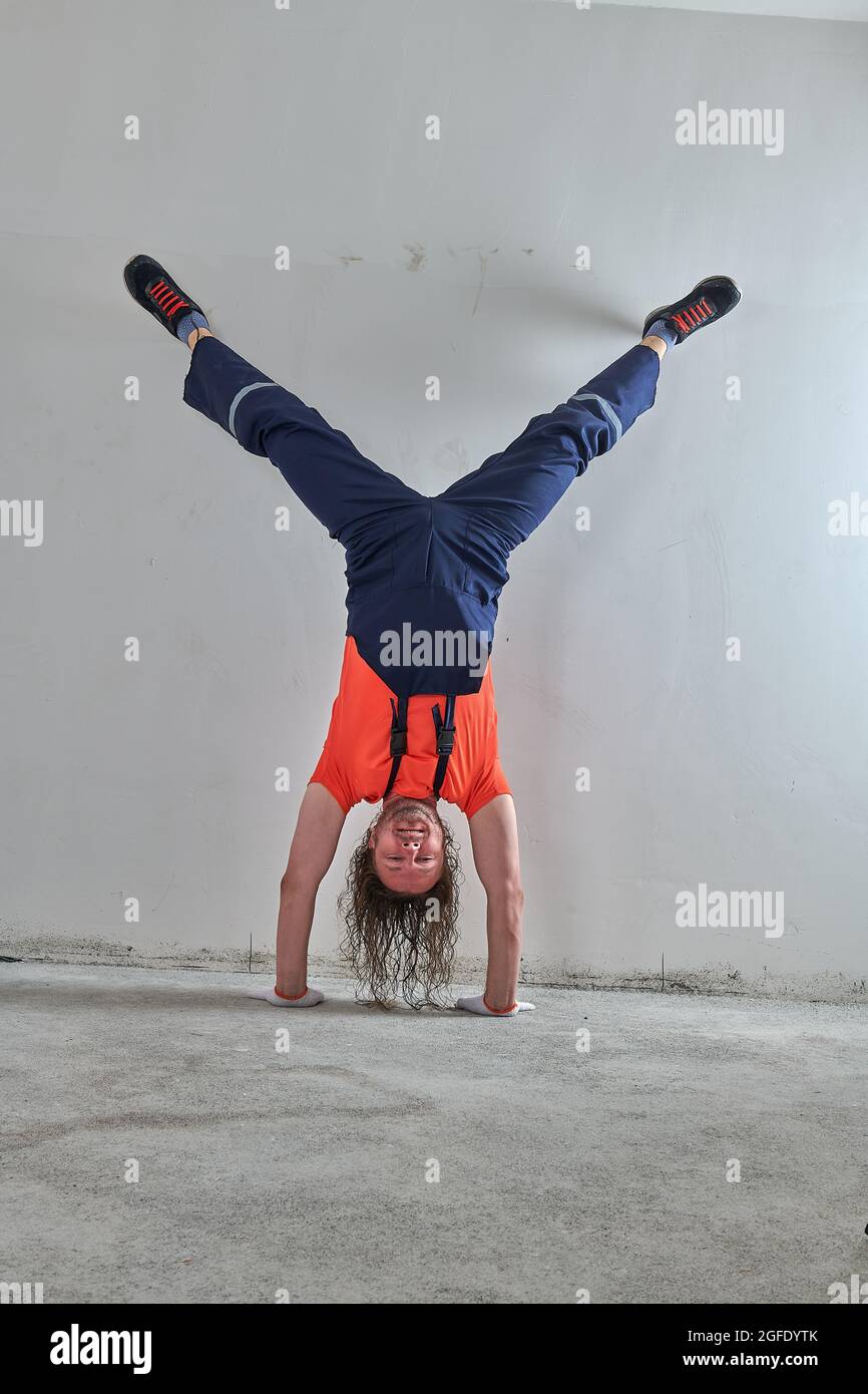 Der ursprüngliche Vorarbeiter in einem orangefarbenen T-Shirt steht auf dem Kopf Stockfoto