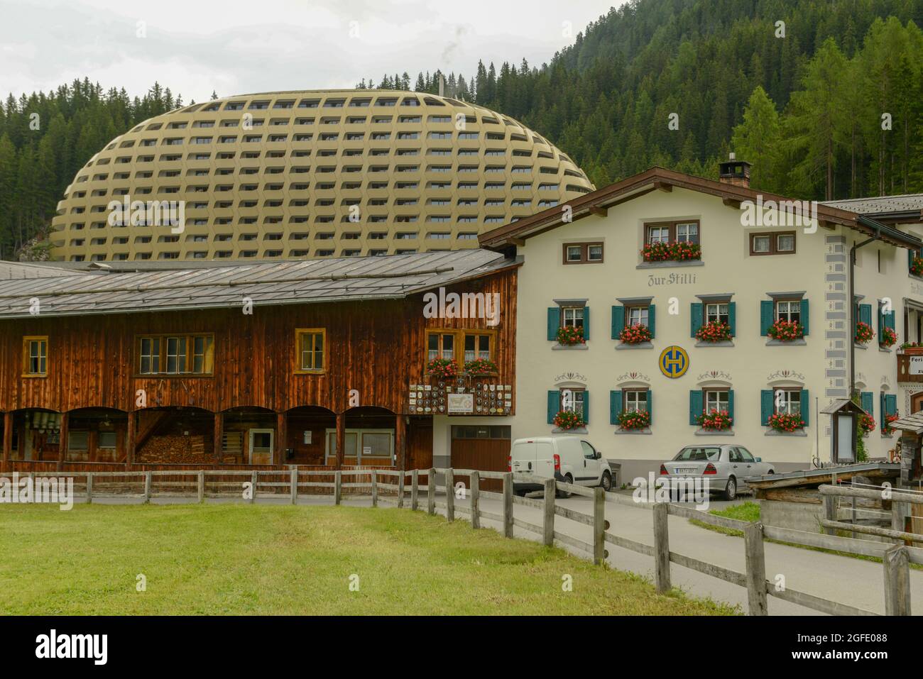 Davos, Schweiz - 8. Juli 2021: Traditionelles Haus vor dem modernen Hotel InterContinental in Davos an den Schweizer alpen Stockfoto