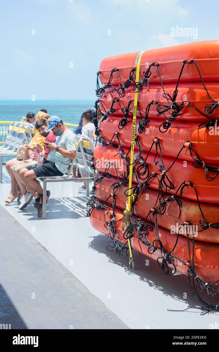 Eine Gruppe von Passagieren, die in der Nähe der Rettungsboote der Fähre in Mexiko sitzen. Selektiver Fokus, vertikaler Bildschirm. Stockfoto