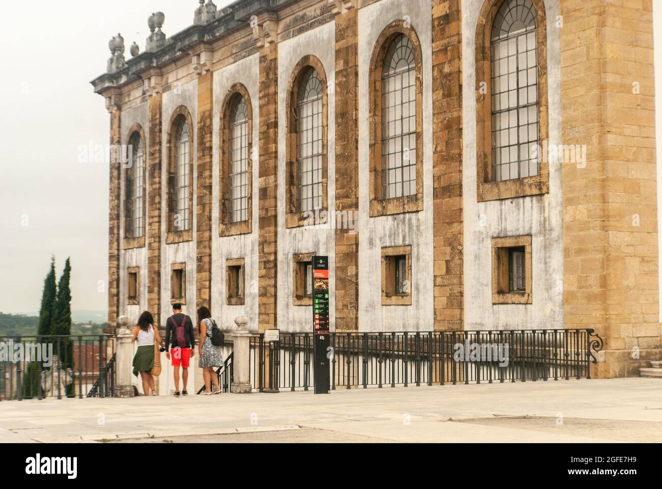 Touristen in der Nähe des Eingangs der Joanina-Bibliothek am Platz der Universität von Coimbra, die die Treppe hinunter gehen, bewölktes Wetter - Portugal Stockfoto