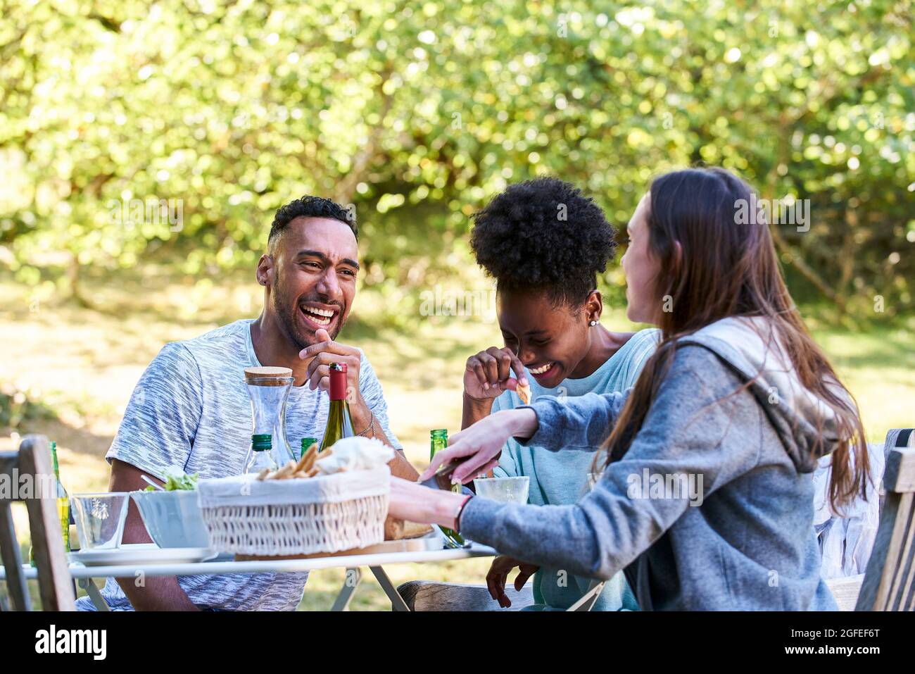 Lächelnde junge Freunde, die im Park essen Stockfoto