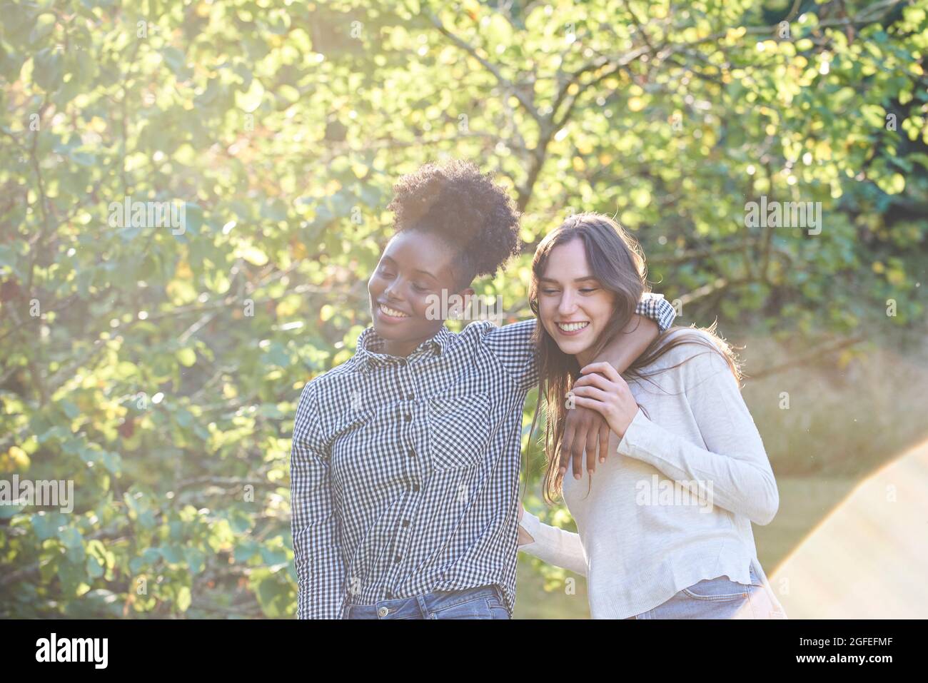 Lächelnde junge Freunde, die im öffentlichen Park spazieren Stockfoto