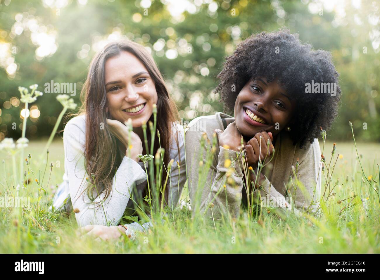 Porträt lächelnder junger Freundinnen, die im Park liegen Stockfoto