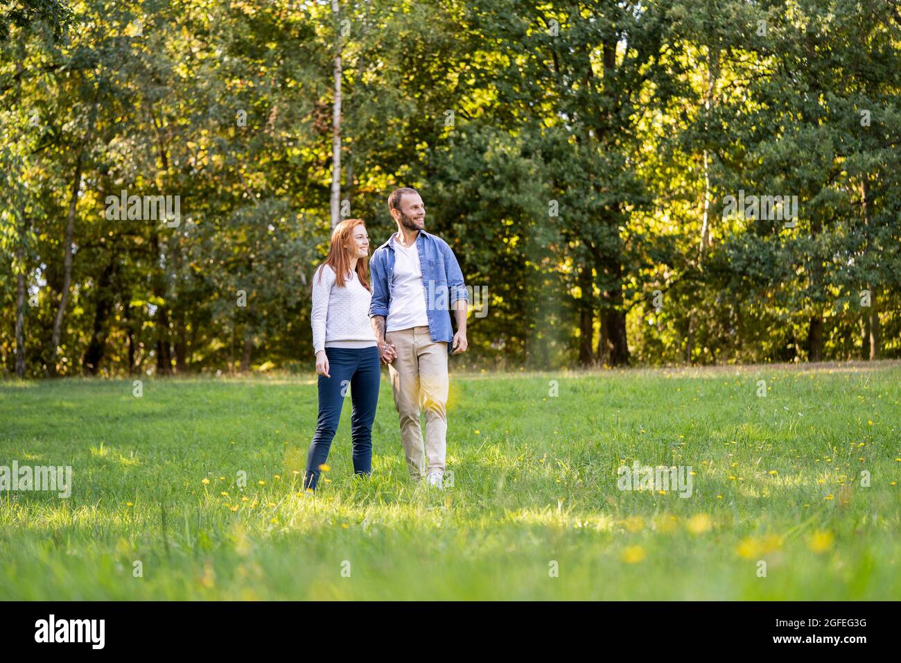 Lächelndes junges Paar, das einen Spaziergang in einem Park genießt Stockfoto