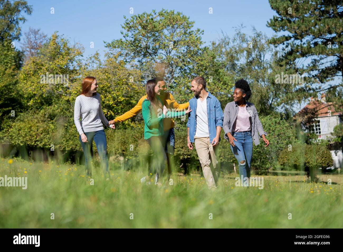 Glückliche junge Freunde, die Spaß haben, während sie zusammen im Park spazieren gehen Stockfoto