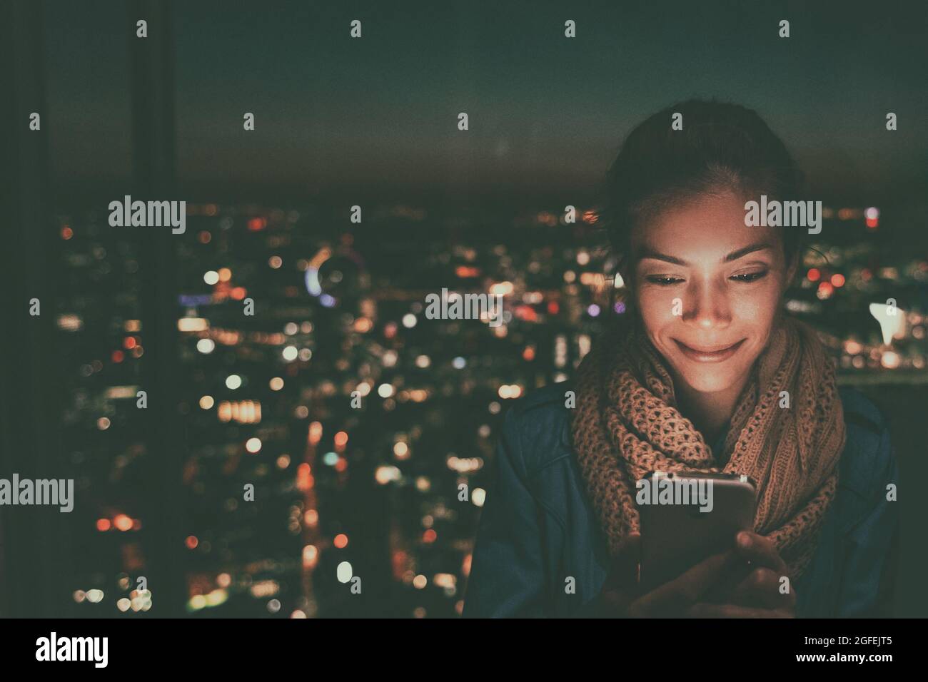 Handy asiatische Frau Blick auf den hellen Bildschirm des Mobiltelefons in der Nacht in der dunklen Stadt hellen Hintergrund Handy-Smartphone. Technologie-Kontakt, der Personen in aufspürt Stockfoto