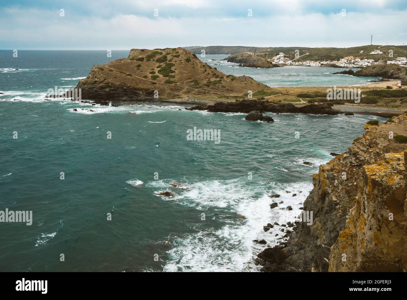 Felsige Strandlandschaft bei Sturm mit bewölktem Himmel. Dramatische, lange Exposition von Meereswellen, die auf Felsen brechen. Stockfoto