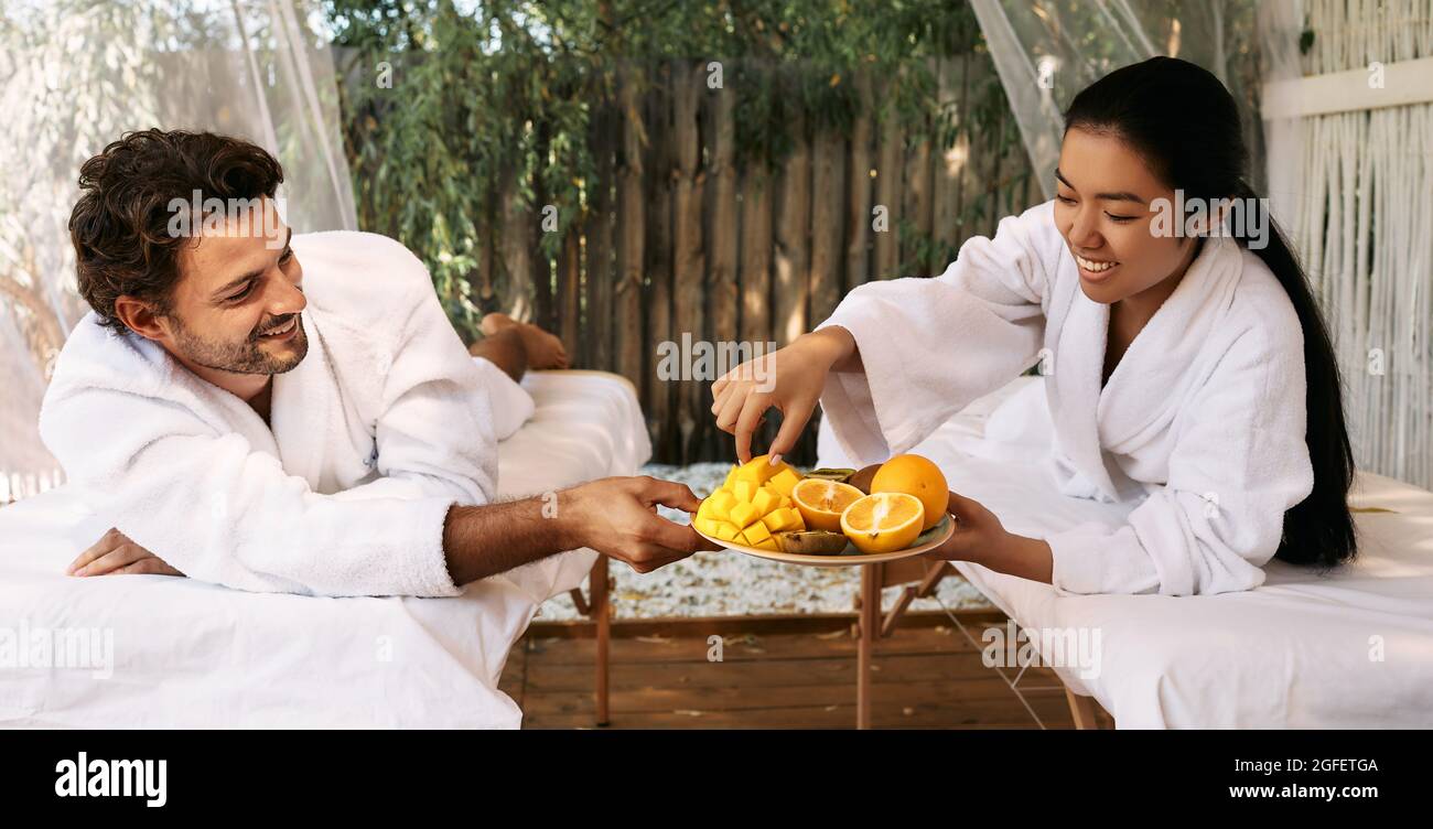 Asiatische Frau mit ihrem hübschen Freund, der im Spa Resort exotische Früchte isst. Ein Paar während einem romantischen Wochenende auf Bali Stockfoto