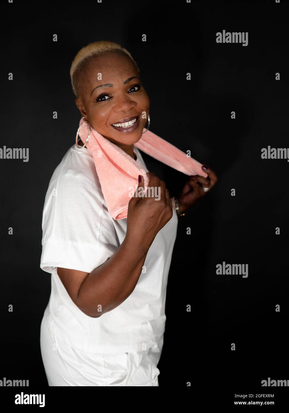 Profilansicht einer lächelnden, schönen afroamerikanischen Frau, die Sportkleidung trägt und ein Handtuch hält Stockfoto