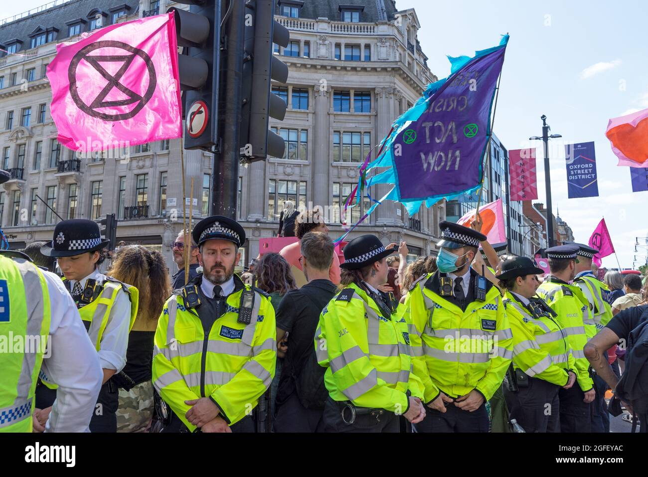 Extinction Rebellion Protestierende am Oxford Circus protestieren gegen den Klimawandel. Die Polizei blockierte den Protest mit Flaggen, die hinter dem Protestmarsch hinaufflogen. Stockfoto