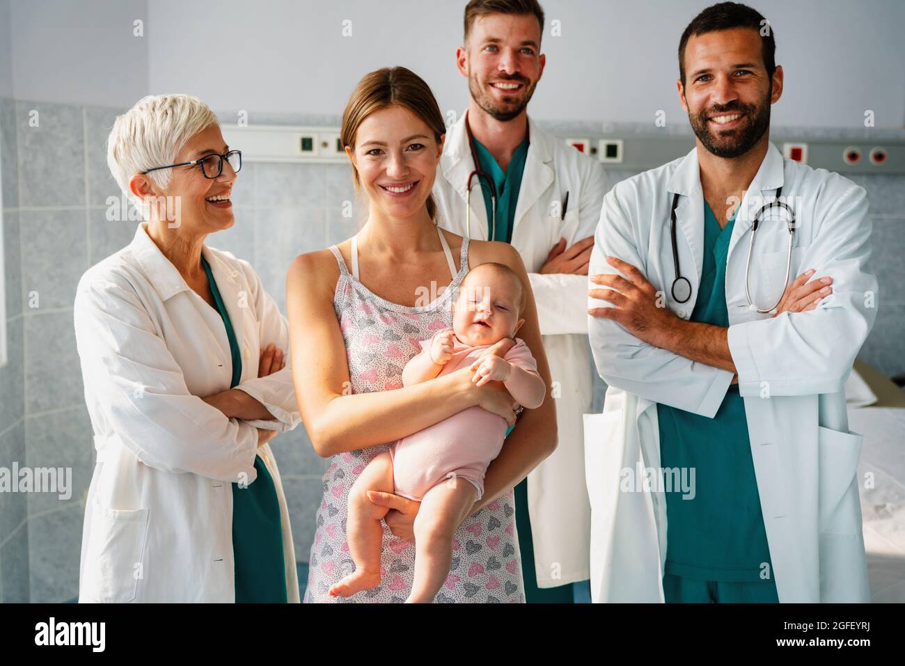 Portrait des selbstbewussten medizinischen Teams mit Baby und Elternteil bei Krankenhaus Stockfoto