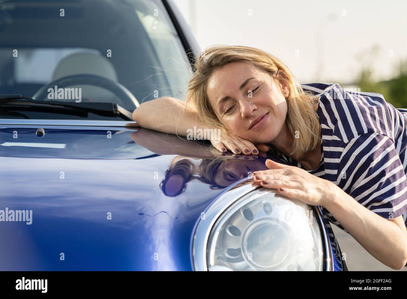 Mittlere Frau Fahrer umarmt Haube des Autos nach Detaillierung, Polieren. Werbung für Kfz-Versicherungen Stockfoto