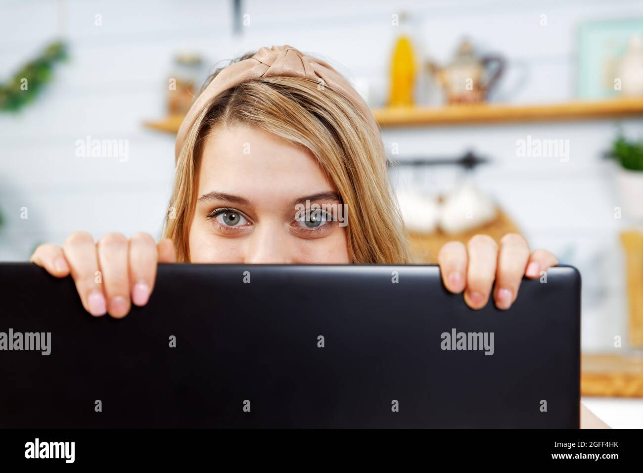 Nahaufnahme eines Mädchens, das hinter einem Laptop aus der Nähe guckt. Copyspace. Stockfoto