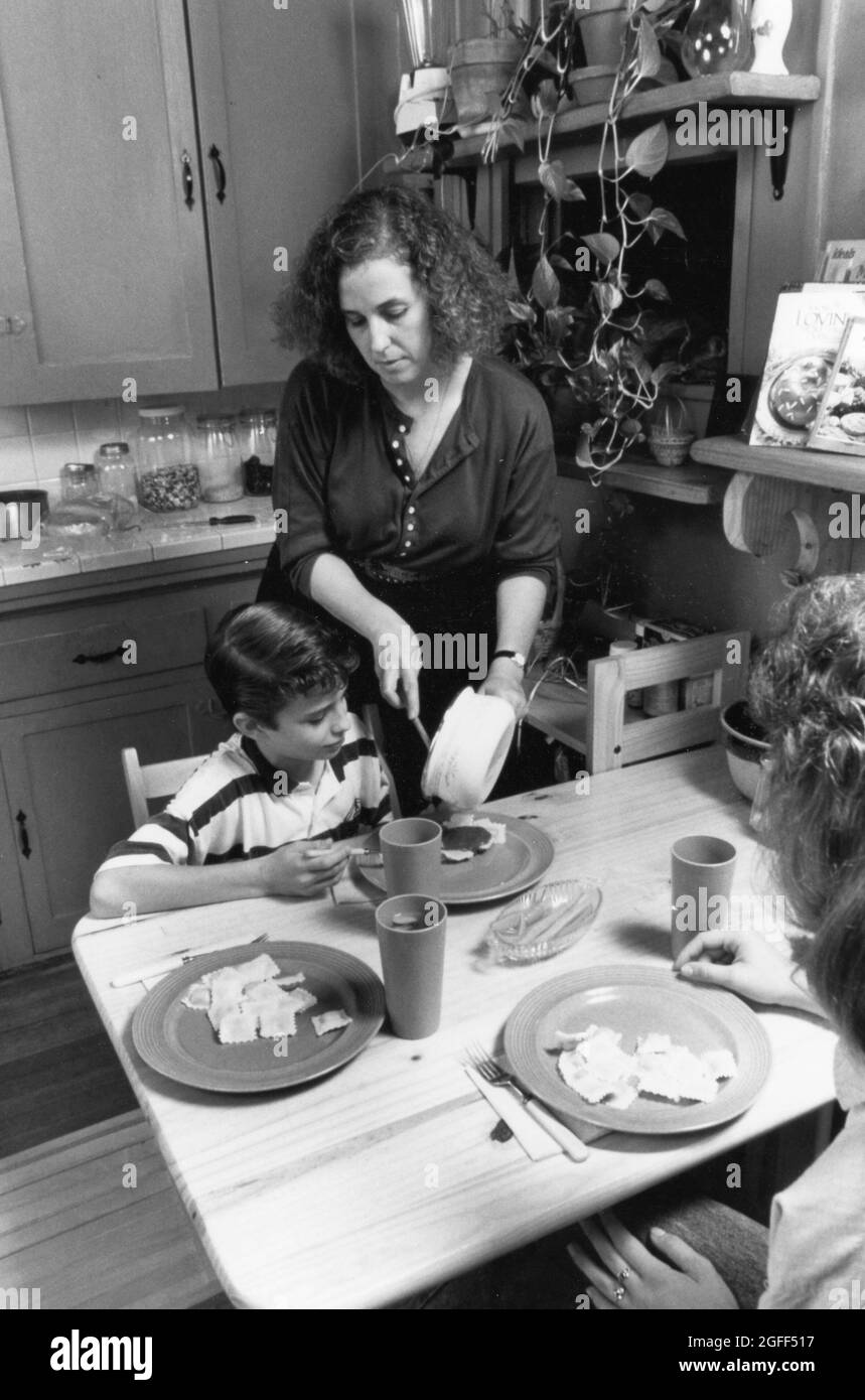 Austin Texas USA, um 1990: Alleinerziehende Mutter und Kinder essen in ihrer Küche zu Abend. Original in Farbe ©Bob Daemmrich Stockfoto