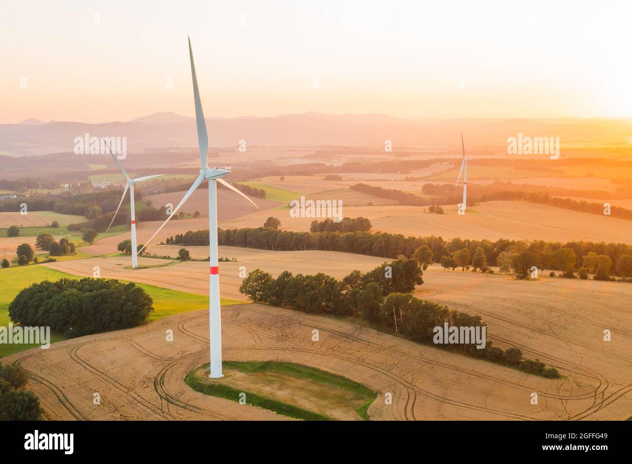 Panoramablick auf Windmühlen oder Windkraftanlagen für die Stromerzeugung bei herrlichem Sonnenuntergang auf dem Feld. Umweltfreundliche Erzeugung erneuerbarer Energien. Stockfoto