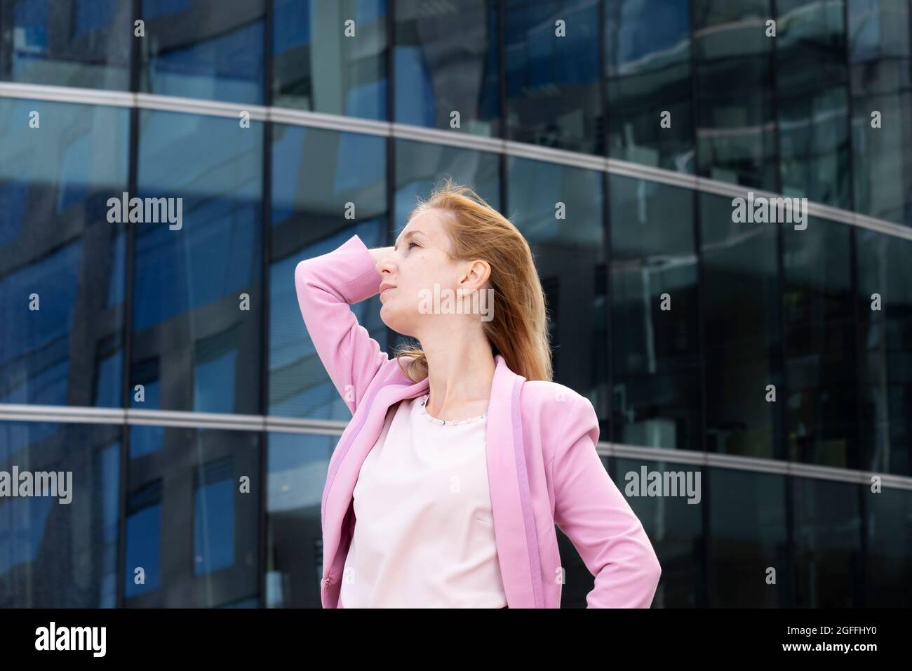 Junge schöne blonde Frau mit langen Haaren in rosa elegante Kleidung Stockfoto