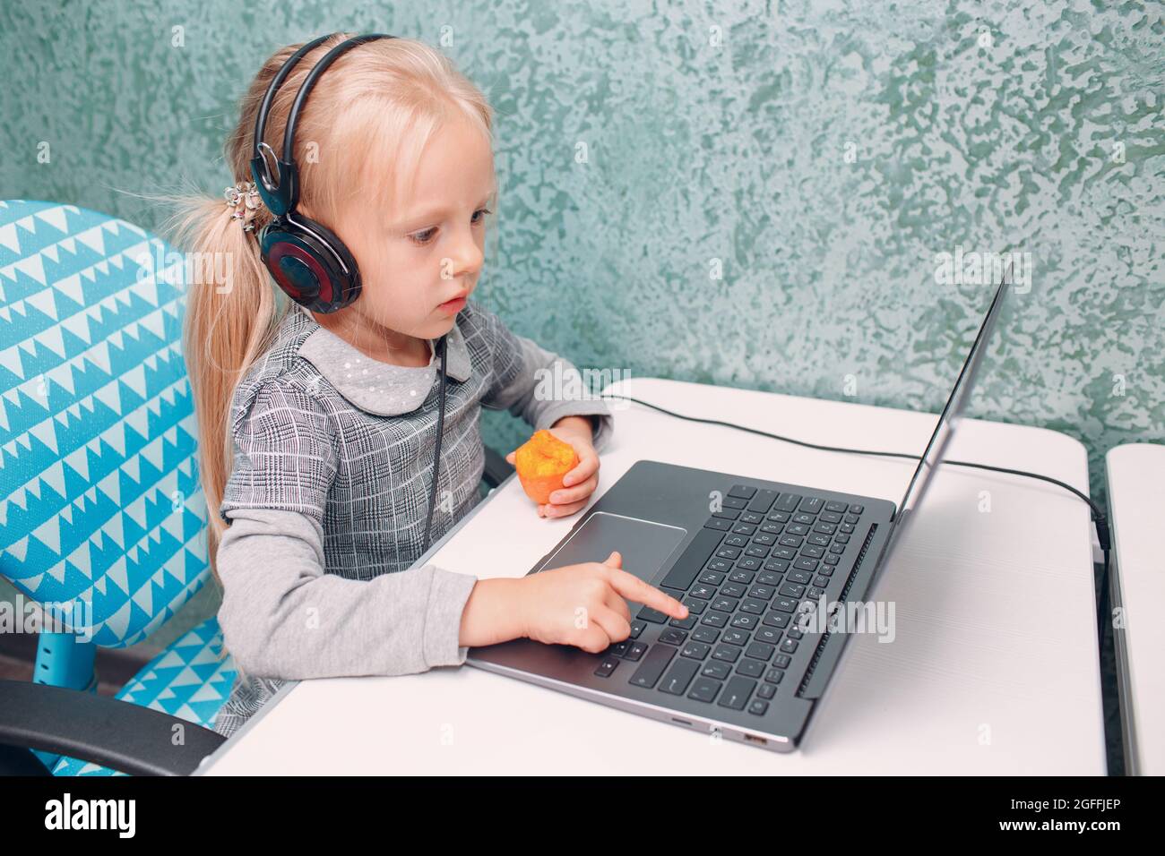 Junge Studentin kleines Mädchen mit Karotte in der Hand eingeben Laptop-Tastatur lernen und die Vorbereitung zurück zur Schule. Stockfoto