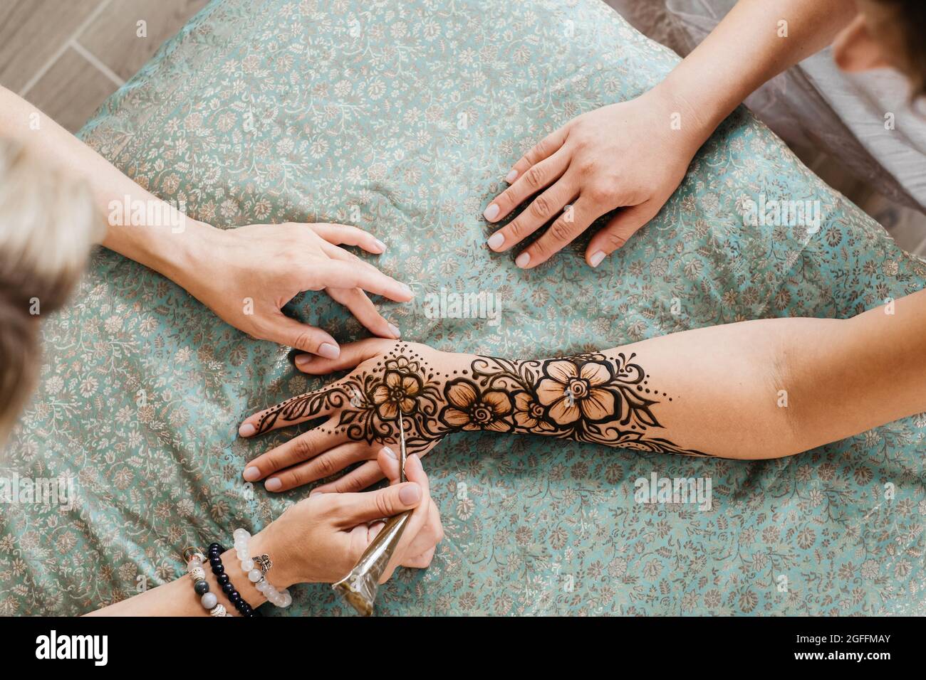 Mehndi Künstler Zeichnung floralen Henna Tattoo auf Frau Hand im Schönheitssalon. Meister, der traditionelle Mehendi-Muster für die Braut vor der Hochzeit anwendet. Stockfoto