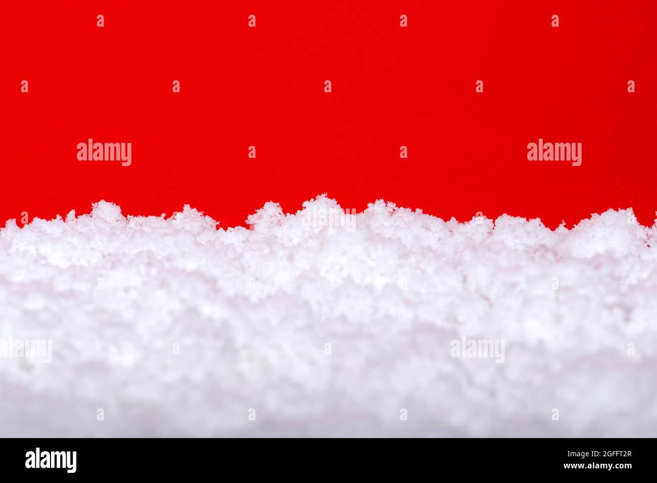 Schnee auf rotem Hintergrund. Weihnachtsthema, Großformat, Panoramafoto für ein Banner oder Website-Header. Weihnachtskarte zum Drucken. Stockfoto