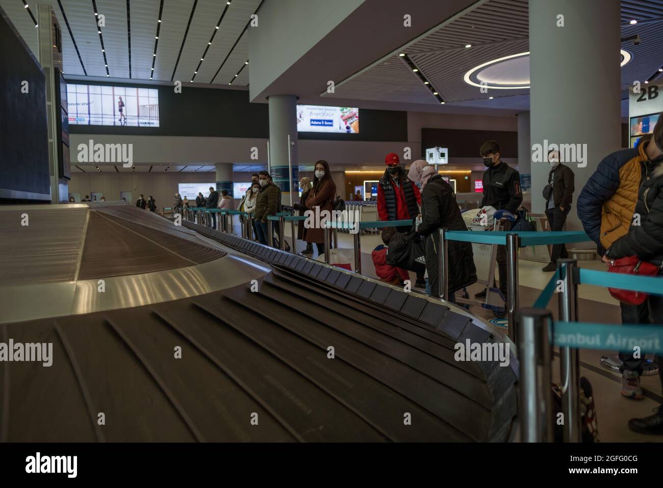 Arnavutkoy, Istanbul, Türkei - 03.11.2021: Passagiere mit Schutzmasken warten in der Nähe des Istanbul Airport Gepäckkarussells pla auf ihr Gepäck und ihre Taschen Stockfoto