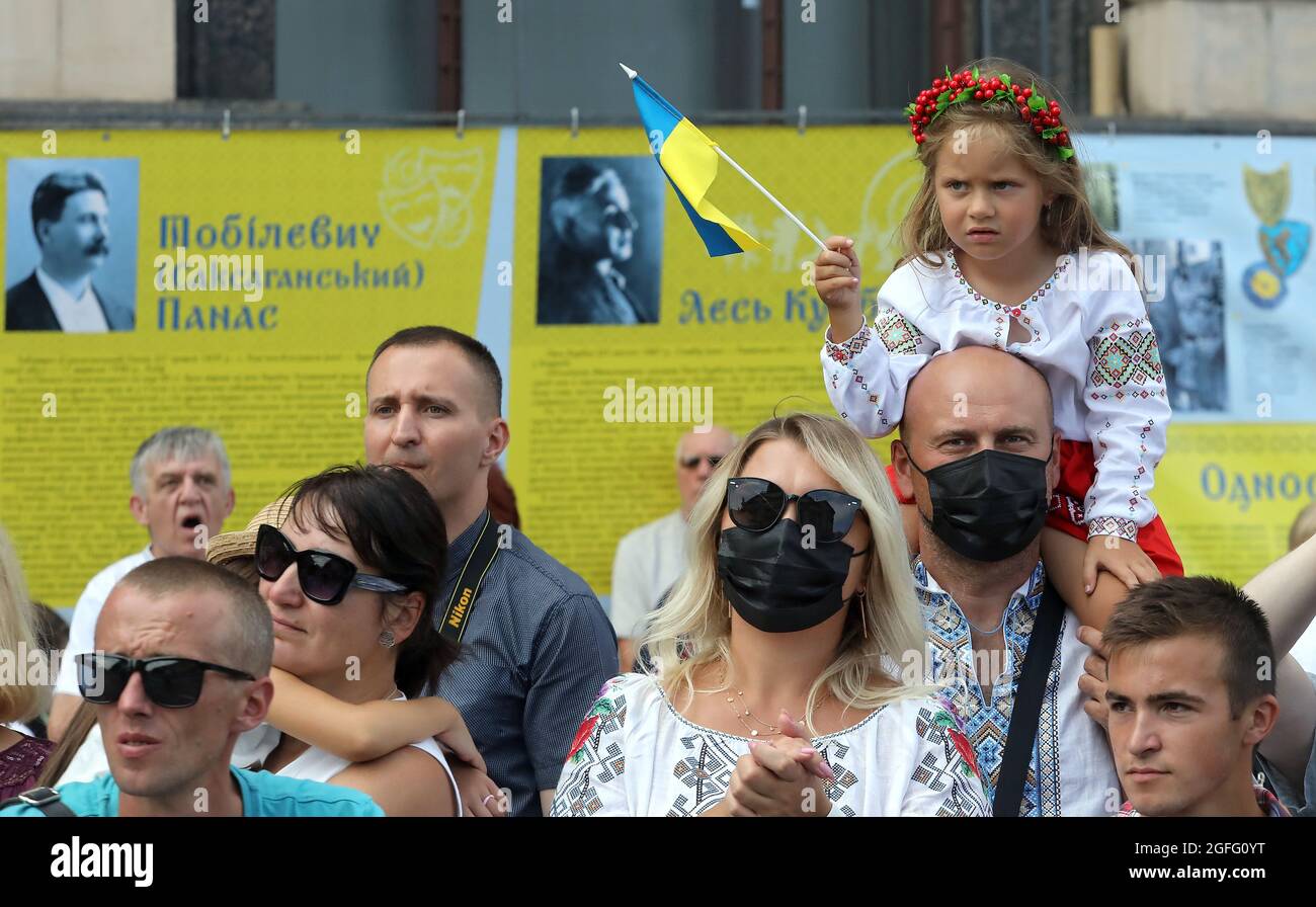 Nicht exklusiv: KIEW, UKRAINE - 24. AUGUST 2021 - EIN Mädchen mit einer Miniatur-Flagge der Ukraine sitzt während des Marsches der Verteidiger auf den Schultern des Mannes Stockfoto