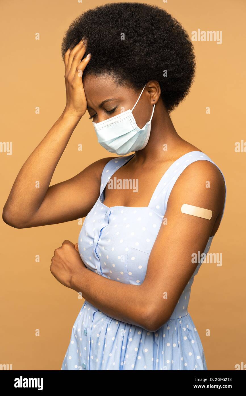 Schwarzes Mädchen in Gesichtsmaske denkt an Nebenwirkungen nach der Impfung von covid-19, zweifelnd Stockfoto