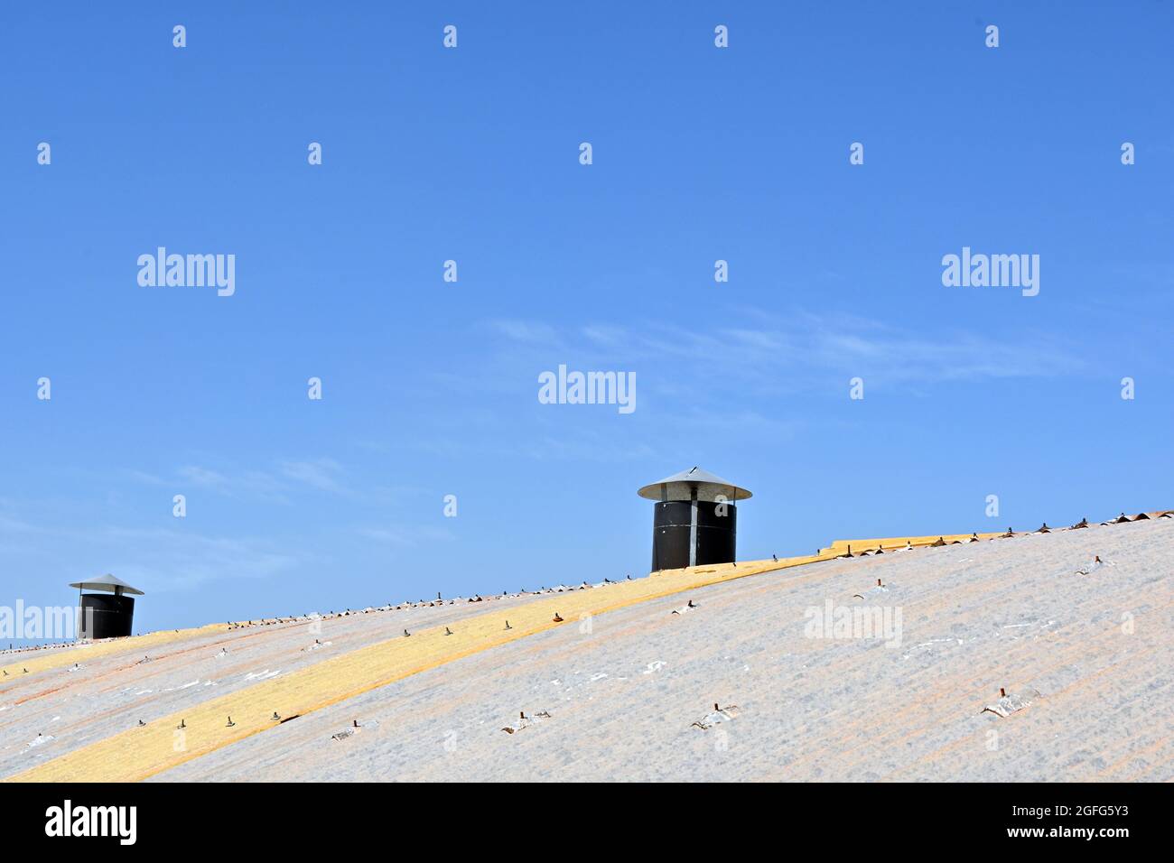 Belüftungssystem auf dem Blechdach des industriellen Fabrikschuppens. Blauer Himmel. Stockfoto