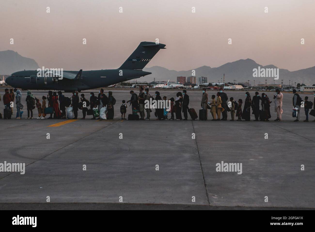 Evakuierte warten während einer Evakuierung auf dem Hamid Karzai International Airport, Kabul, Afghanistan, am 23. August auf den Einsteigen in eine Boeing C-17 Globemaster III. US-Dienstmitglieder unterstützen das Außenministerium bei einer nicht-kämpferischen Evakuierungsoperation (NEO) in Afghanistan. (USA Marine Corps Foto von Sgt. Isaiah Campbell) Stockfoto