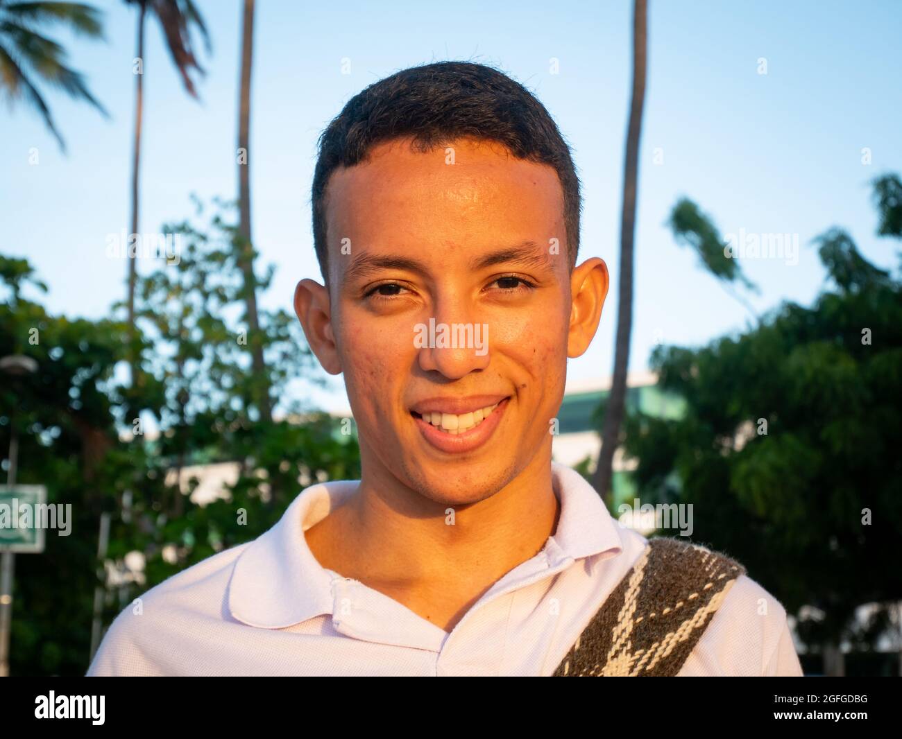 Ryohacha, La Guajira, Kolumbien - Mai 26 2021: Porträt eines jungen Lateinamerikaners, der bei Sonnenuntergang mit blauem Himmel die Kamera anschaut Stockfoto