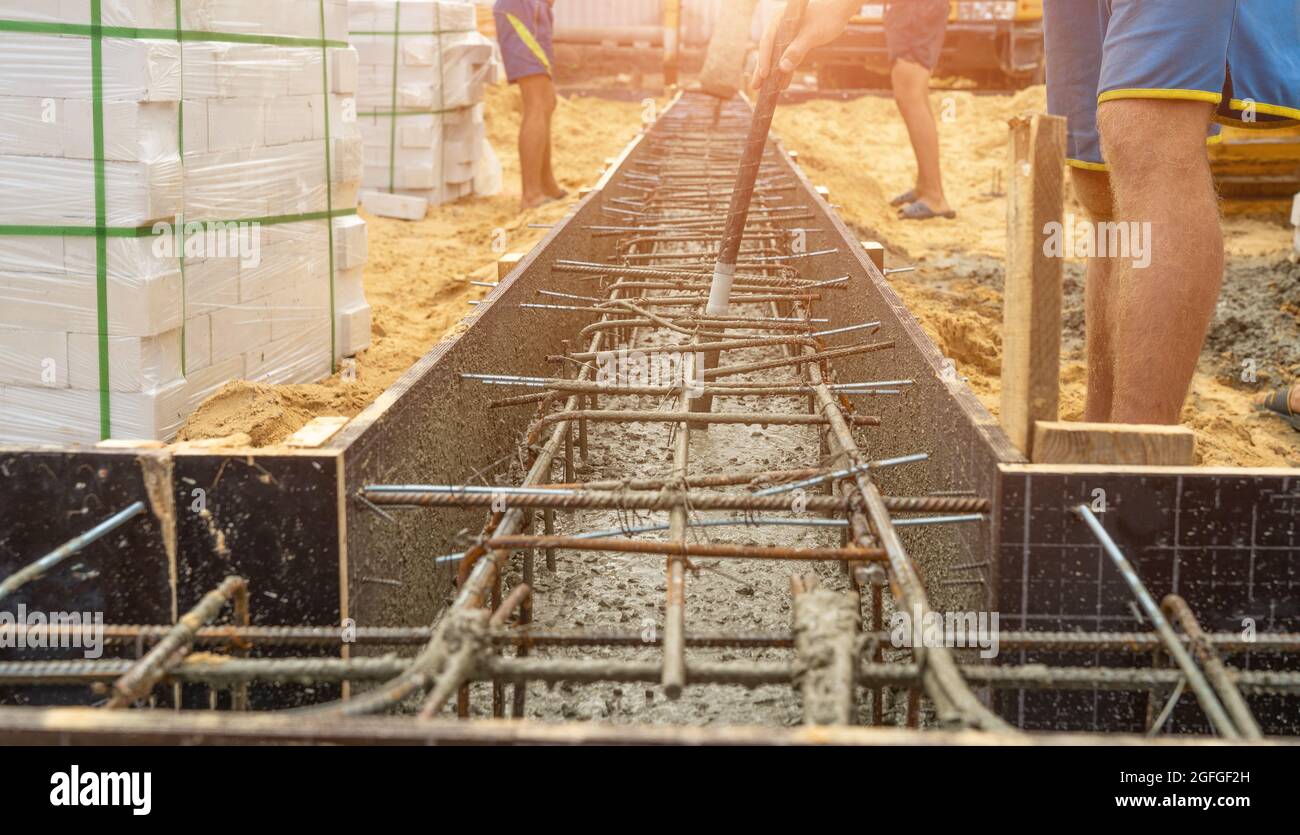 Gießen von Zement oder Beton mit automatischer Pumpe, Baustelle mit verstärktem Gitter-Fundament, Beginn des neuen Hausbaus. Stockfoto