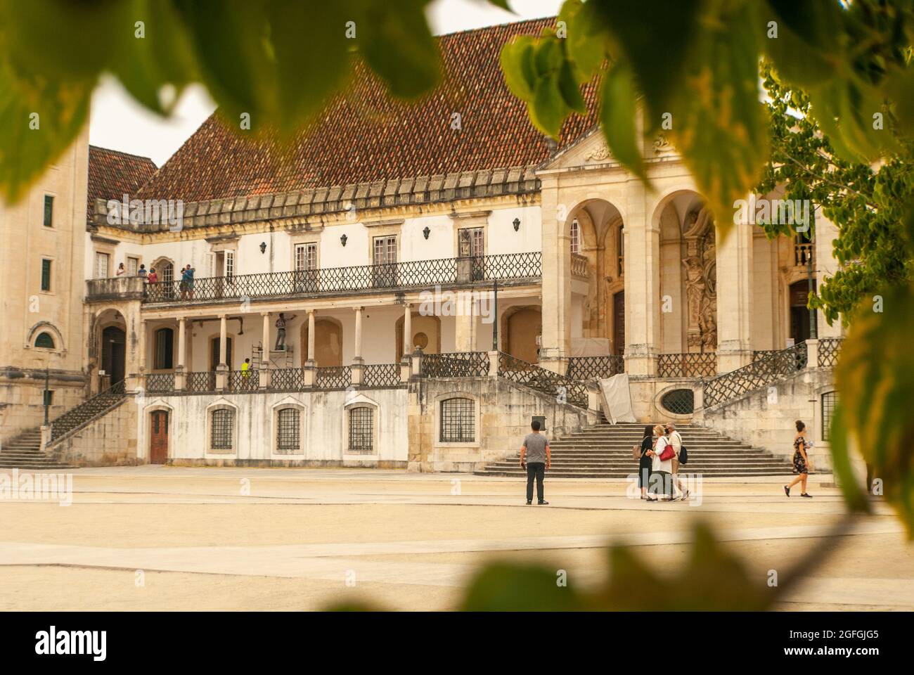 Blick auf den leeren touristischen Platz Paco das Escolas der Universität von Coimbra durch den Rahmen der Baumblätter - Selective Focus, Portugal Stockfoto