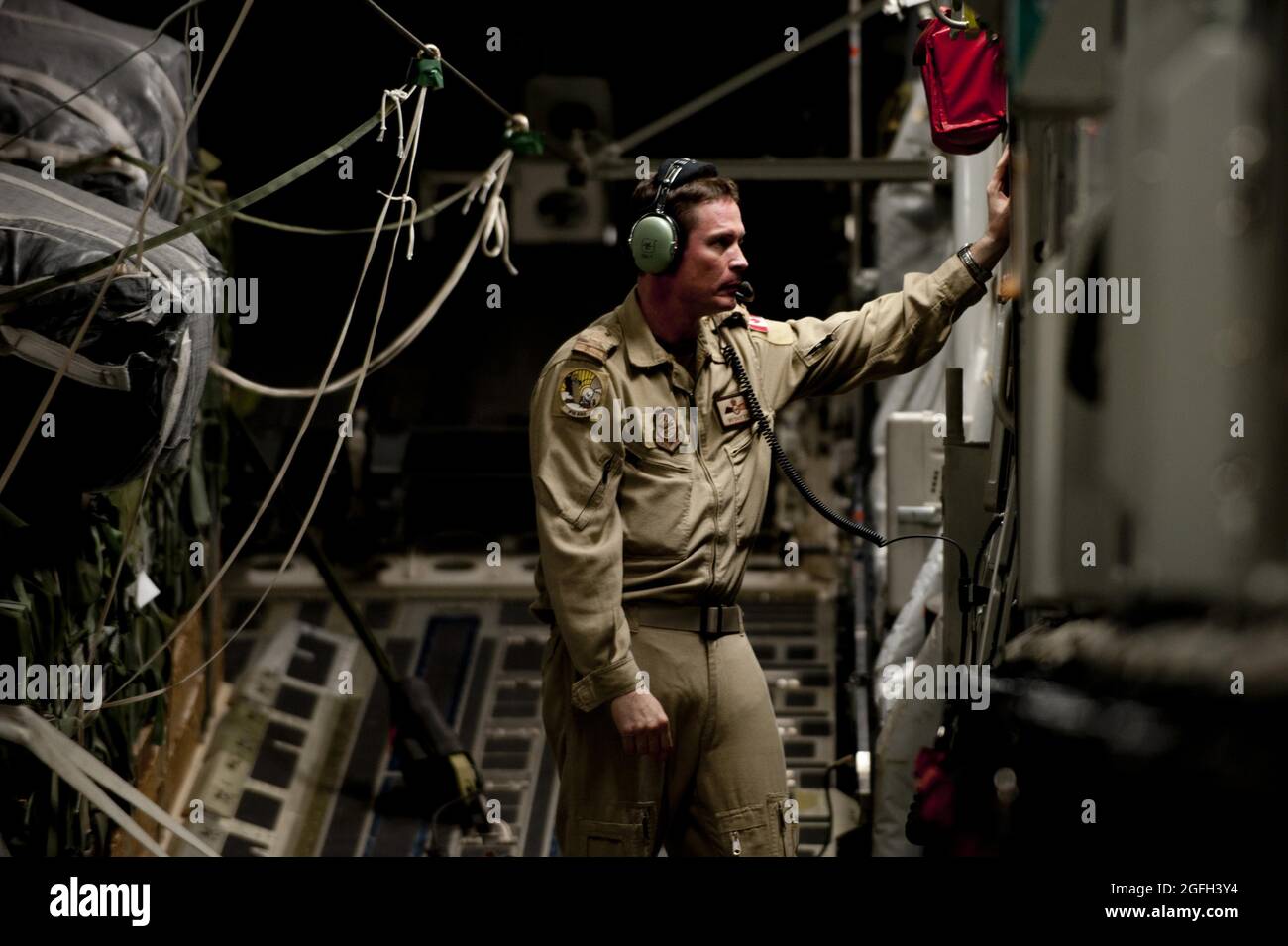 David Daly, Offizier der kanadischen Luftwaffe, 816. Expeditionary Airlift Squadron Loadmaster, überprüft das Kommunikationssystem auf einem C-17 Globemaster III vor einer Luftlieferungsmission nach Afghanistan. Die Luftbesatzung C-17 lieferte Fracht, die aus Treibstoff und anderen verschiedenen Lieferungen bestand, an einen entfernten, vorwärts operierenden Stützpunkt in Afghanistan. Daly wird der amerikanischen Einheit als Teil eines Austauschprogramms zugewiesen, um den C-17-Flugrahmen besser zu erlernen. Stockfoto