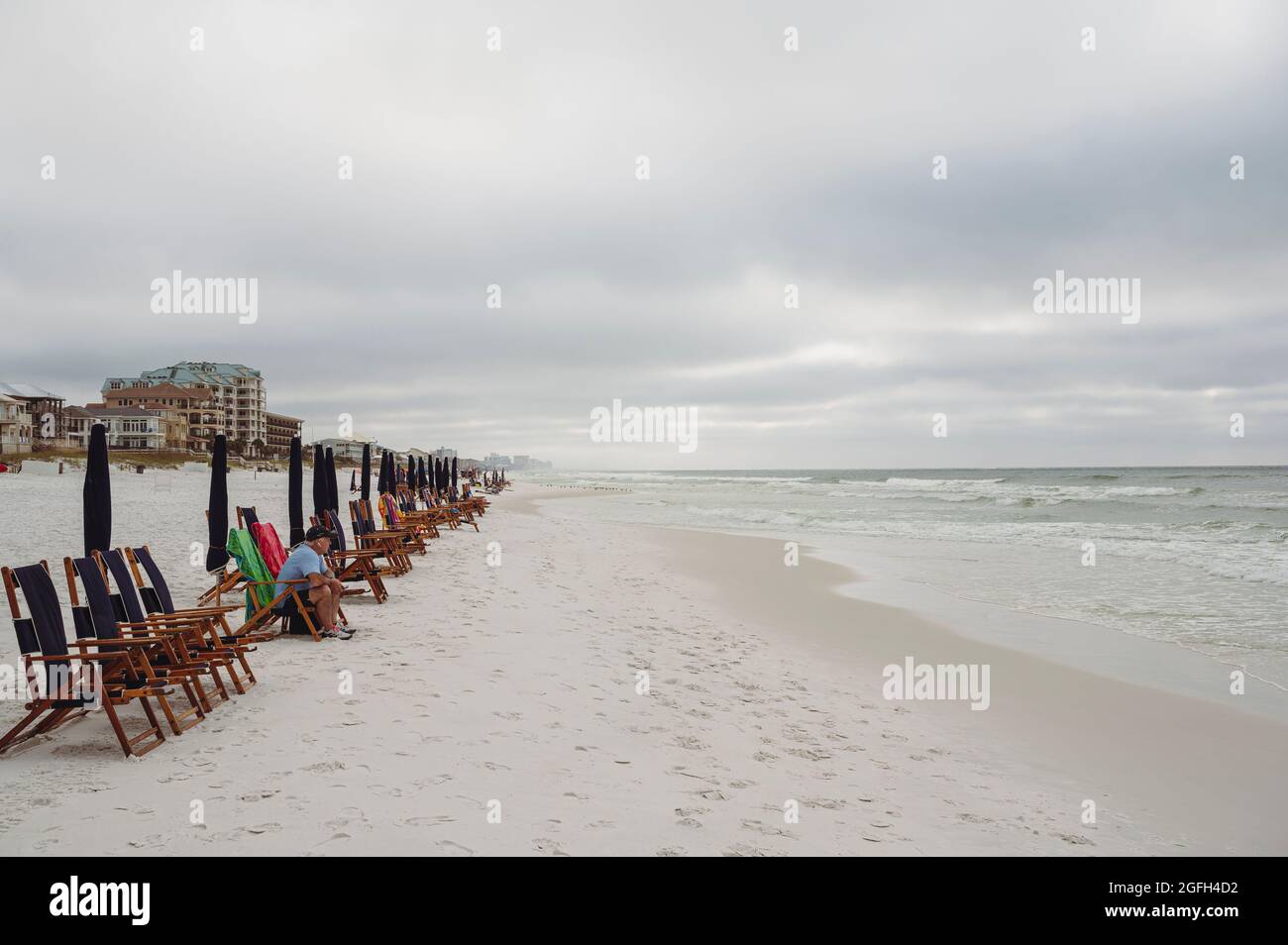 Allein sitzender Mann sitzt während der Pandemie von 2020 allein an einem verlassenen Strand in Destin Florida, USA. Stockfoto