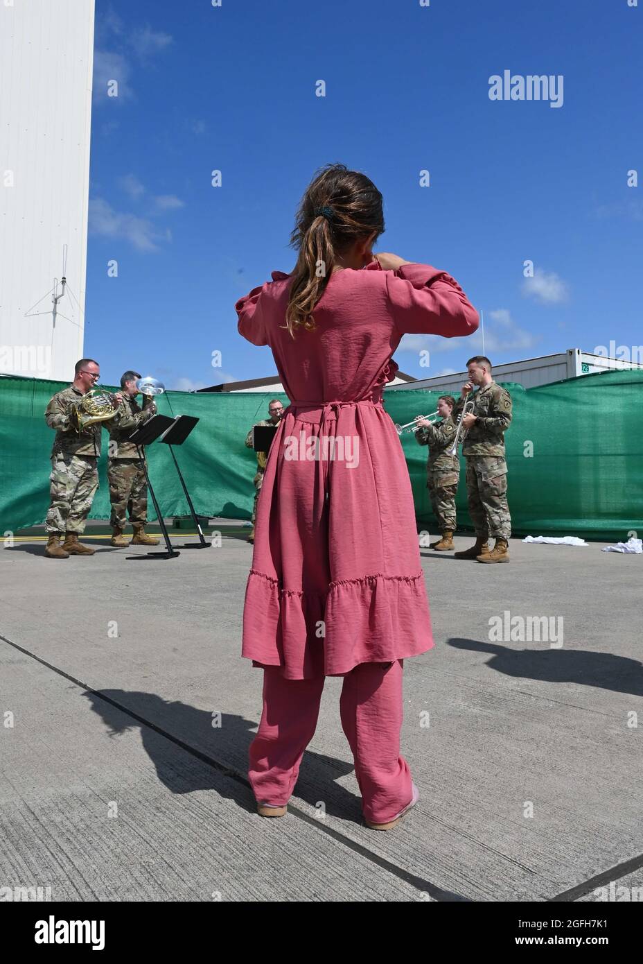 Ein Evakuierungskind beobachtet, wie die US Army Europe and Africa Band und der Chorus während der Operation Allies Refuge auf dem Ramstein Air Base, Deutschland, am 22. August 2021 Musik spielen. Der Soldatenchor der US Army Europe wurde 1963 organisiert, um die Moral durch musikalische Darbietungen zu stärken und erwies sich schnell als erfolgreich bei der Förderung der Beziehungen zwischen der amerikanischen Gemeinschaft in Europa und seinen Gastländern. (USA Luftwaffe Foto von Senior Airman Caleb S. Kimmell) Stockfoto