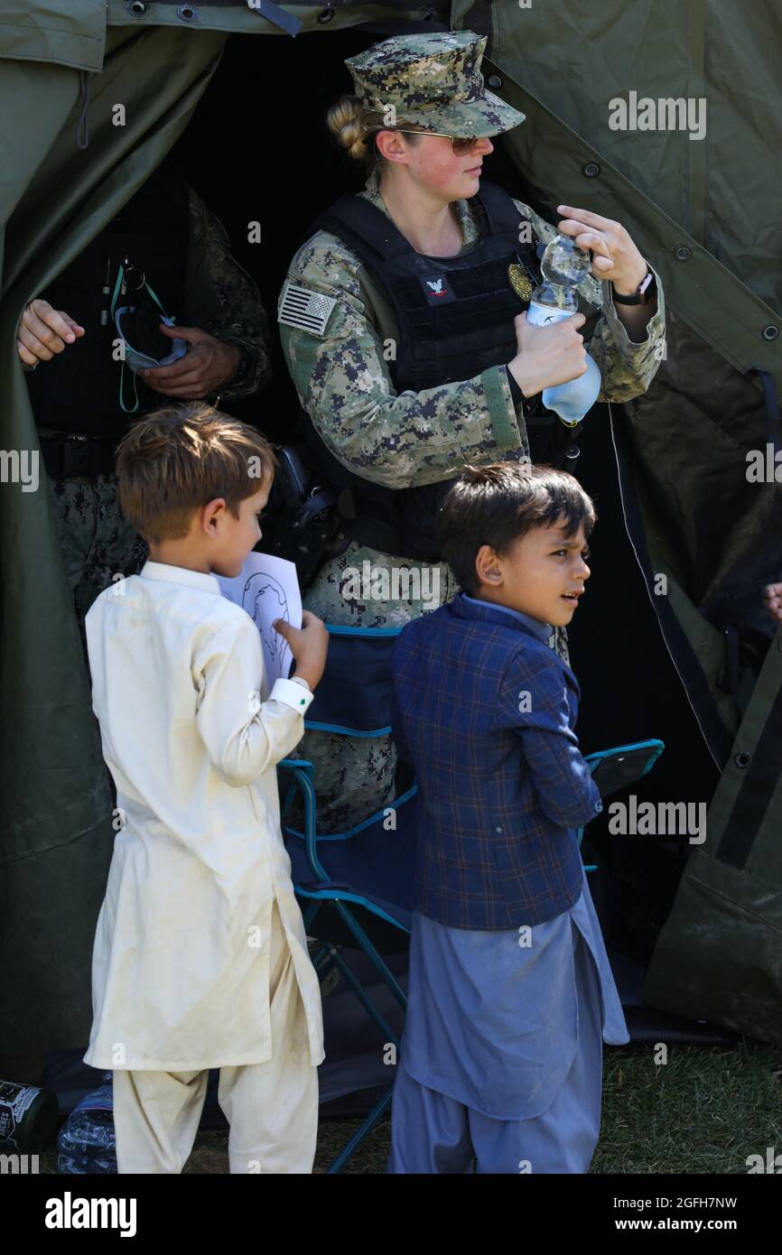 MARINELUFTSTATION SIGONELLA, Italien (Aug 24, 2021) EIN US Navy Sailor öffnet eine Wasserflasche für evakuierte Kinder, 24. August 2021. NAS Sigonella unterstützt derzeit die Mission des Verteidigungsministeriums, um die sichere Ausreise und Umsiedlung von US-Bürgern, Visa-Empfängern für besondere Immigration und gefährdeten afghanischen Bevölkerungen aus Afghanistan zu erleichtern. (USA Navy Foto von Mass Communication Specialist 2nd Class Claire DuBois) Stockfoto