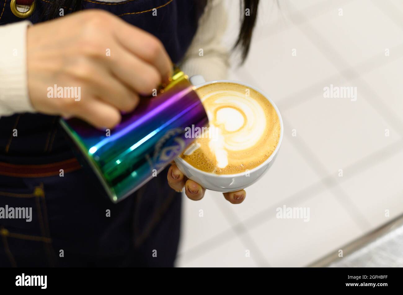 Barista macht Latte oder Cappuccino, gießt Milch und macht Latte-Kunst Stockfoto