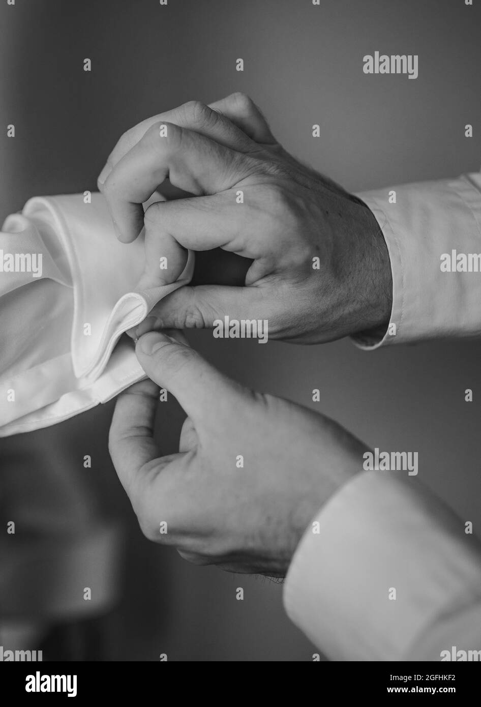 Das verkürzte Foto mit männlichen Händen wird am formellen Hemd mit dem Knopf befestigt Stockfoto